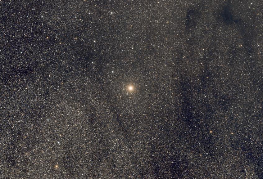 Larawag - Epsilon Scorpii A bright red star on a background of dense faint stars and some dark dust sweeps.