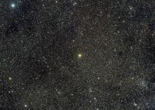 A bright orange star on a background that is dense with faint stars.