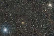 A bright orange sdtar flanked by two even brighter white stars.